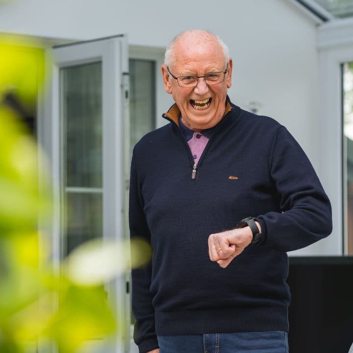 A laughing man checking his HelpAlert watch in his garden